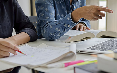 Mujeres trabajando en escritorio con papeles y notebook.